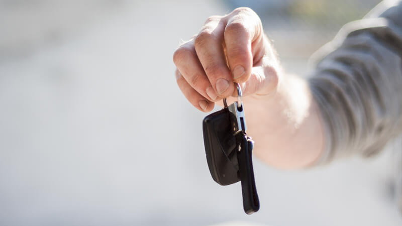 A hand holding a set of keys to a vehicle
